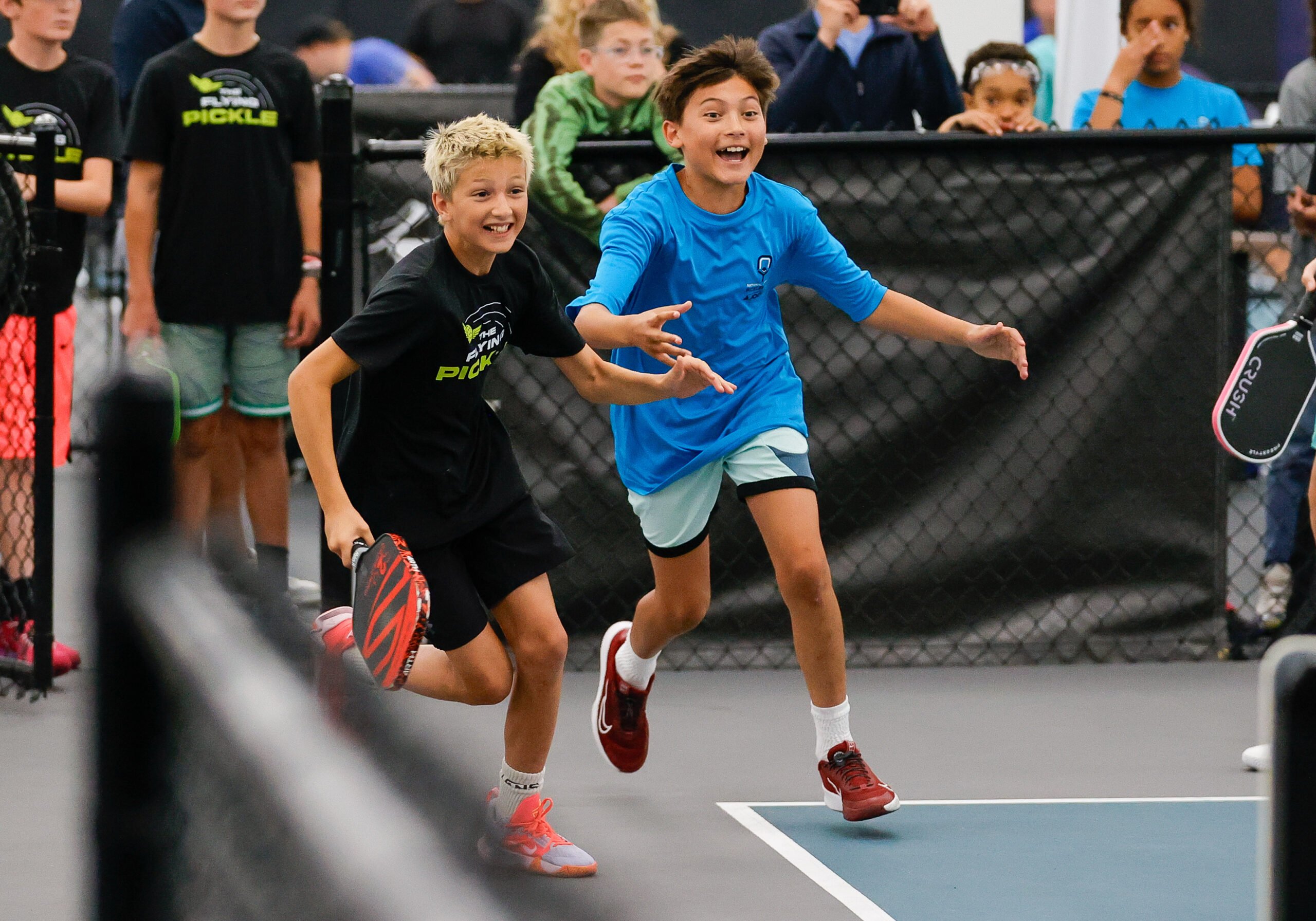 National Junior Pickleball - Two kids joyfully running on a pickleball court